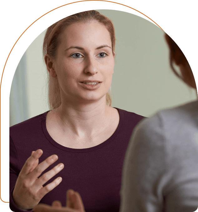 A woman talking to another person in front of a mirror.